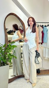 Phụ nữ mặc outfit trắng tối giản trong cửa hàng thời trang, phong cách quiet luxury thanh lịch và tinh tế