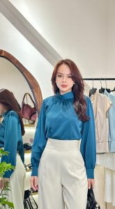 Phụ nữ mặc áo xanh navy và quần trắng theo phong cách quiet luxury, thanh lịch và tối giản