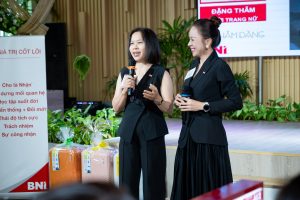 Phụ nữ doanh nhân mặc suit đen thanh lịch phát biểu tại sự kiện, thể hiện hình ảnh phụ nữ thành đạt và chuyên nghiệp